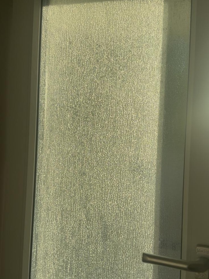 Glastür mit Kalk- und Wasserflecken vor der Reinigung